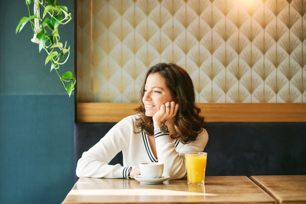 Smiling woman with glass of orange juice sitting at table 
