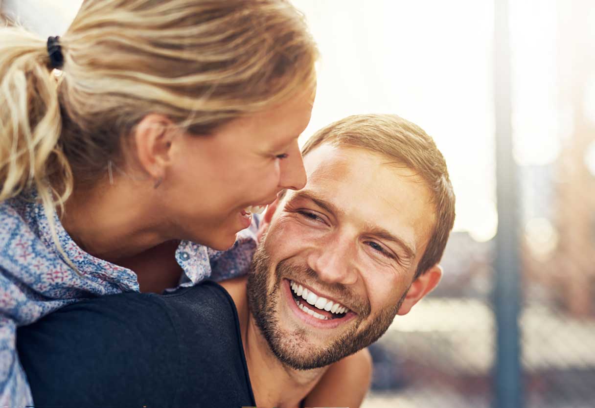 Man with woman on his back, both smiling