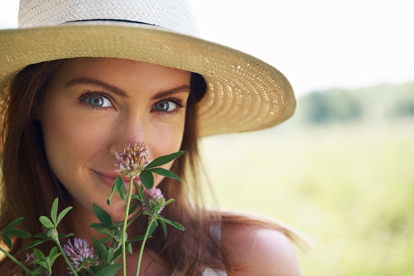 Woman in hat smelling flowers