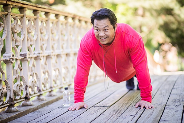 Man in red sweatshirt doing pushups outside