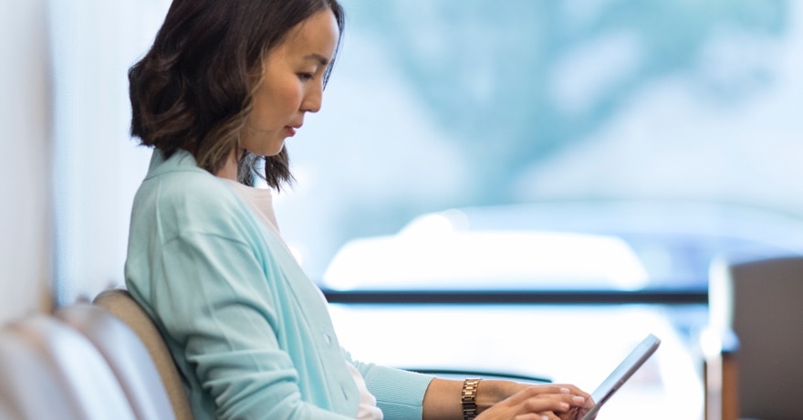 Woman looking at cellphone while she sits in a waiting room