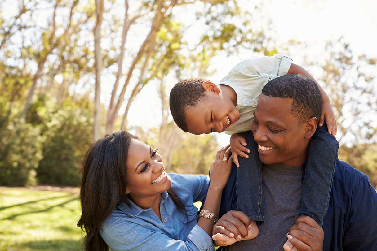 Smiling family standing in front of trees