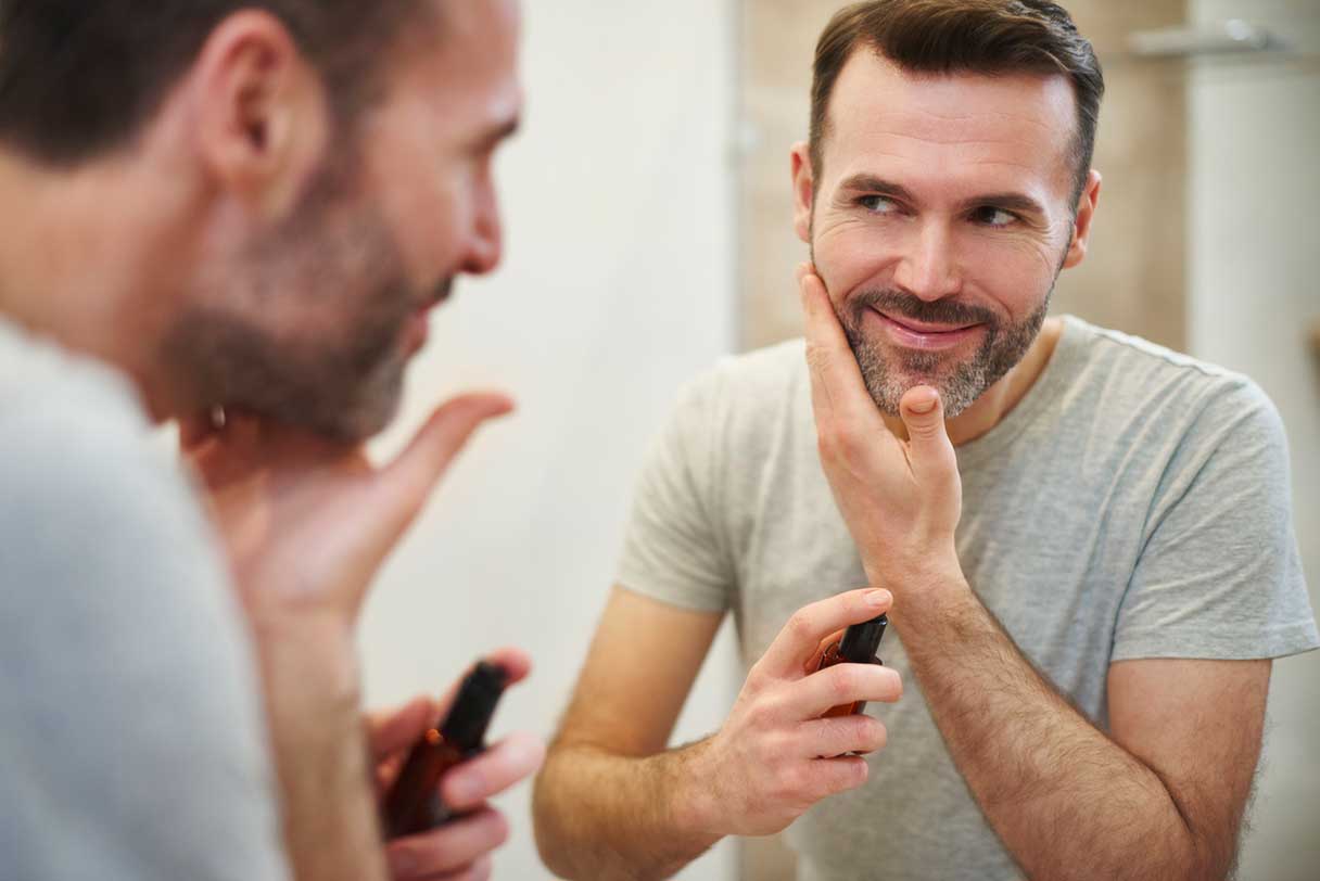 Man looking at his reflection as he applies facial skincare
