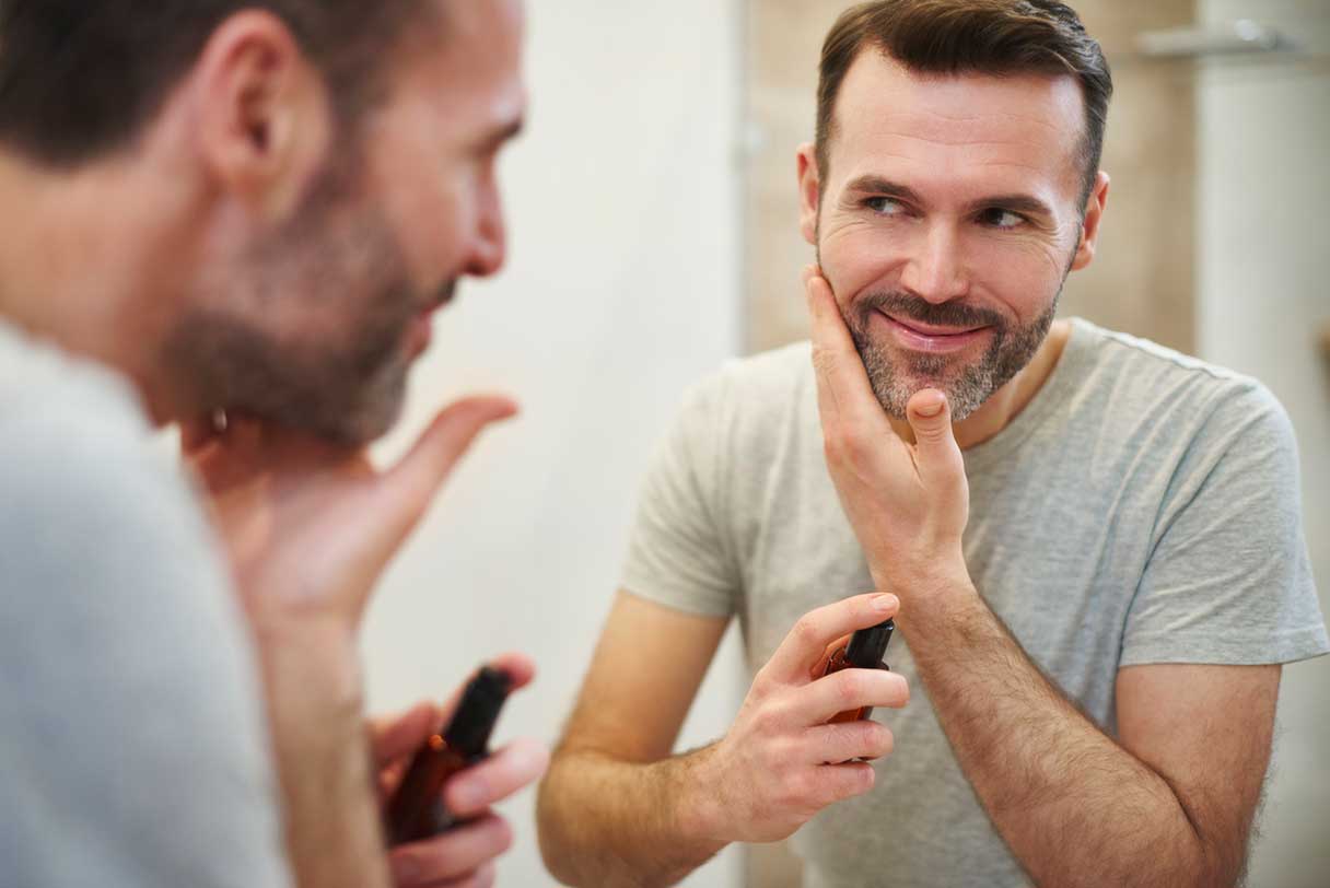 Man looking at his reflection as he applies facial skincare