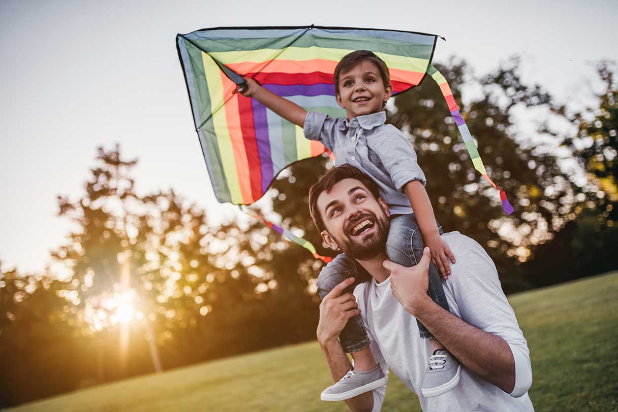 Man holding young boy on his shoulders, holding kite