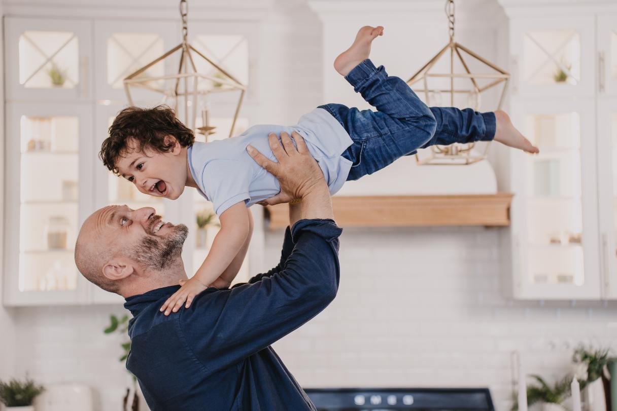 Bald man lifting toddler boy into the air