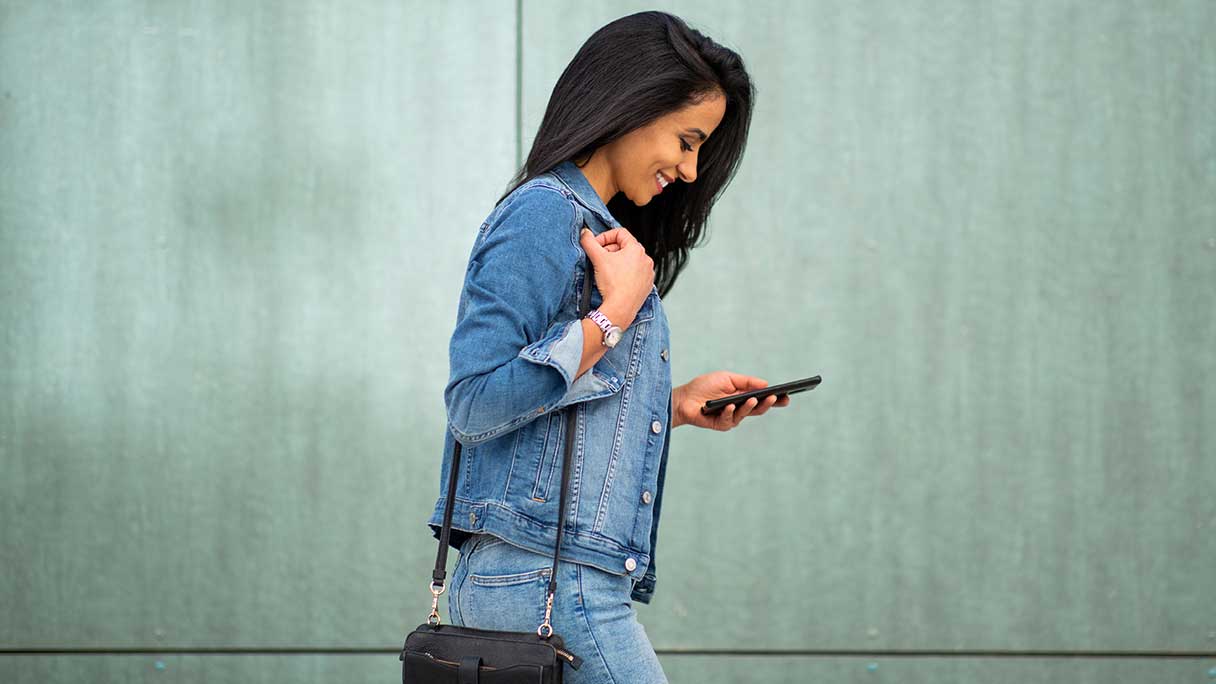 Woman reading her phone as she walks