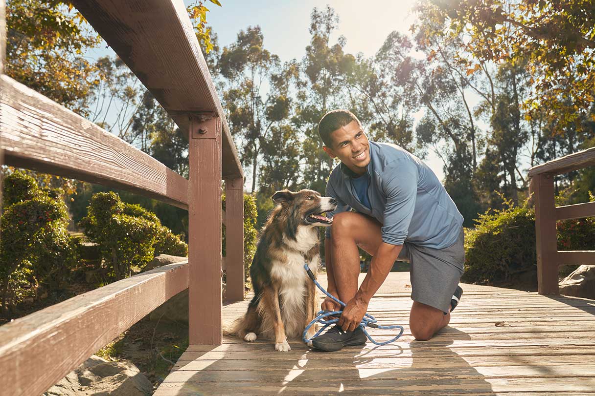 Man kneeling on a bridge next to a dog