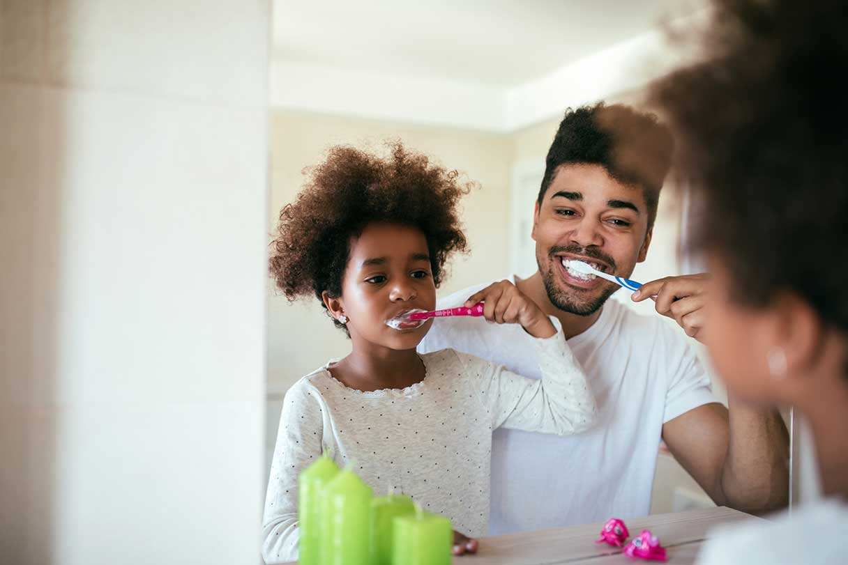 Man brushing his teeth with his daughter