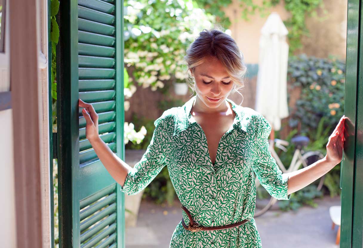 Woman standing between two shutters leading outside