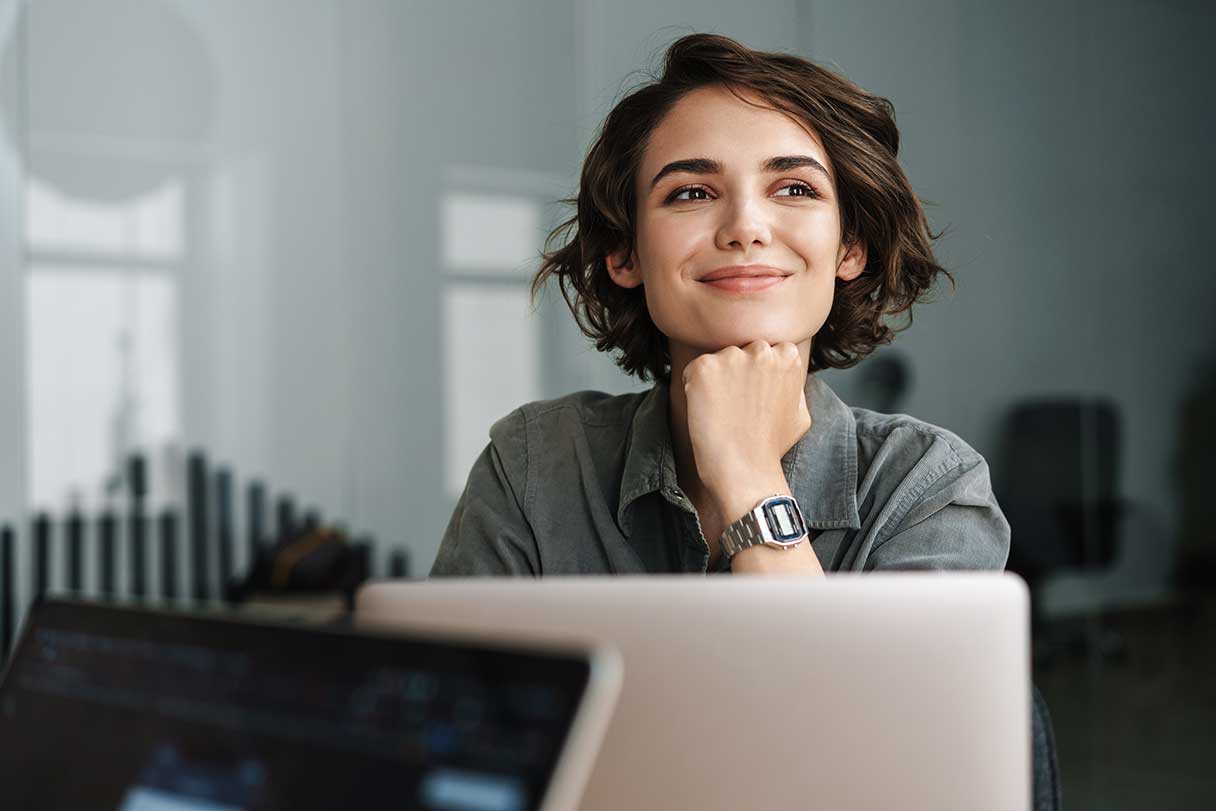 Smiling woman sitting by open laptop