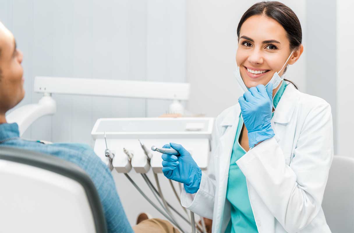 Dentist smiling as she performs dental exam