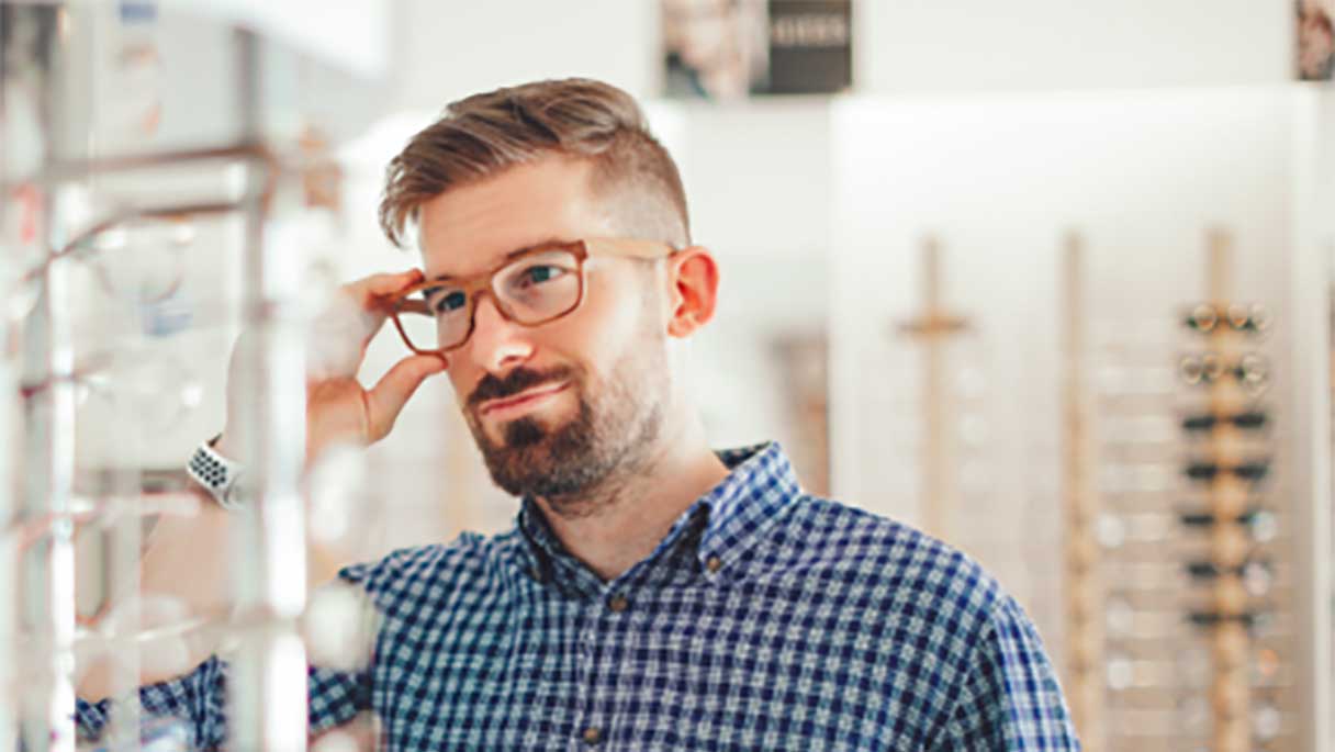 Man trying on glasses in glasses shop
