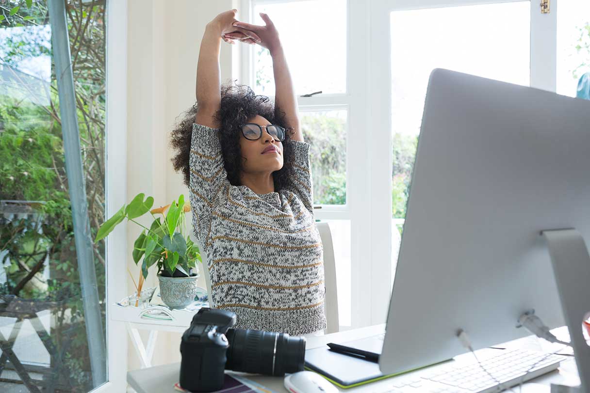Woman stretching in front of computer screen