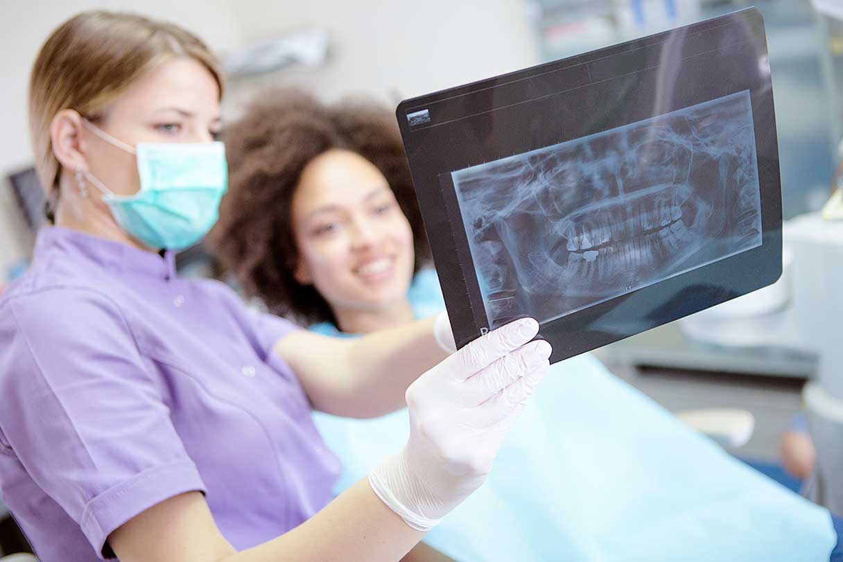 Technician and patient looking at dental x-ray