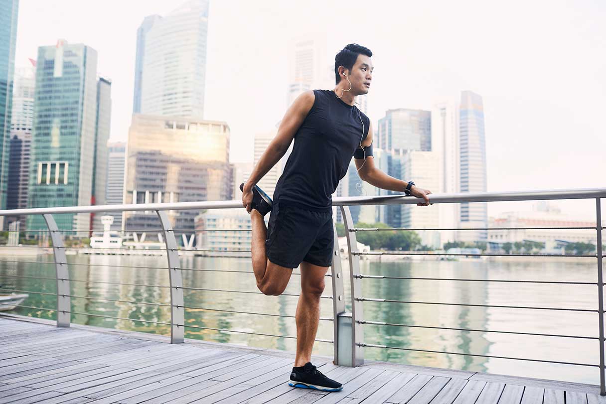 Man leaning against a rail, stretching his leg