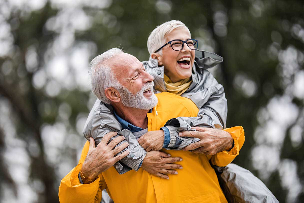 Senior woman with her arms around her partner, both laughing