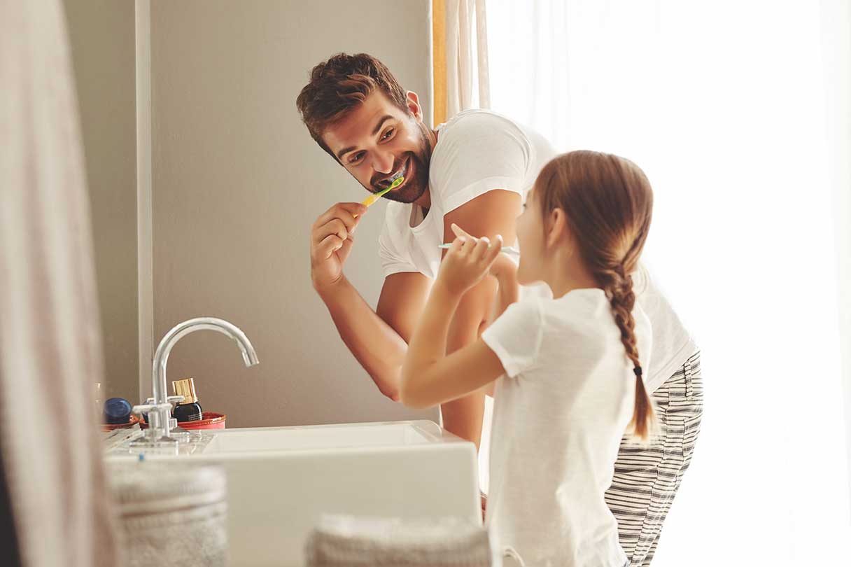 Man brushing his teeth with his daughter
