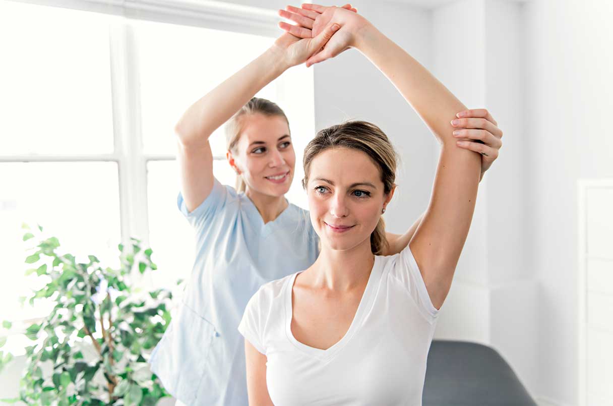 Woman helping another woman stretch out her arm