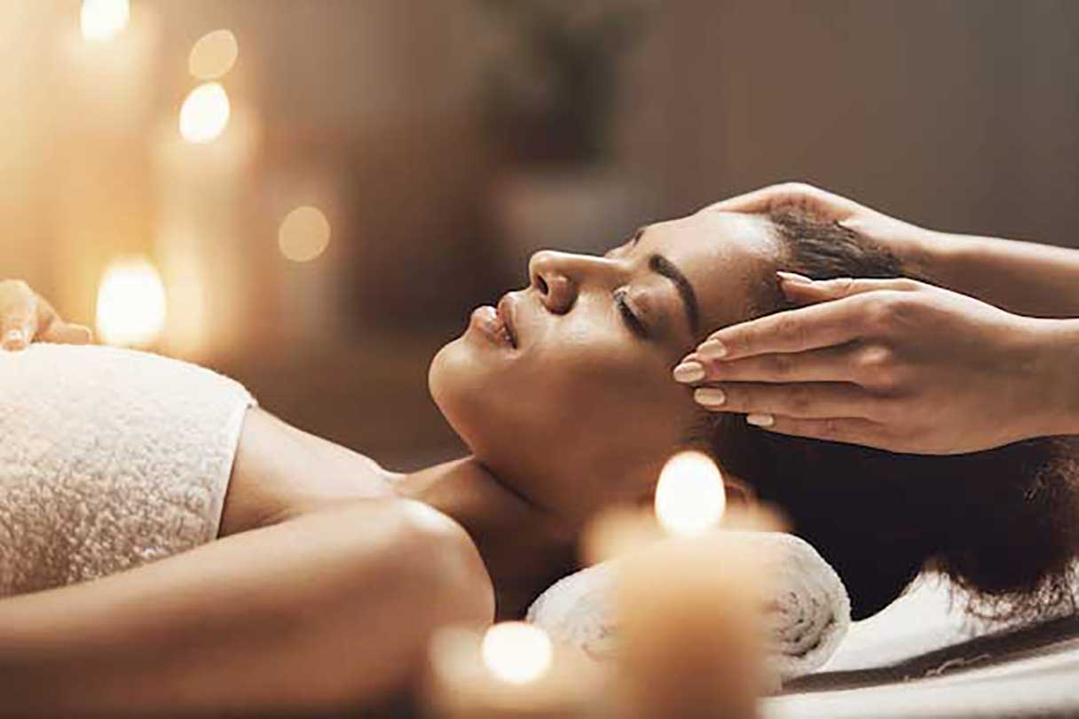 Woman with her eyes closed, receiving massage to temples