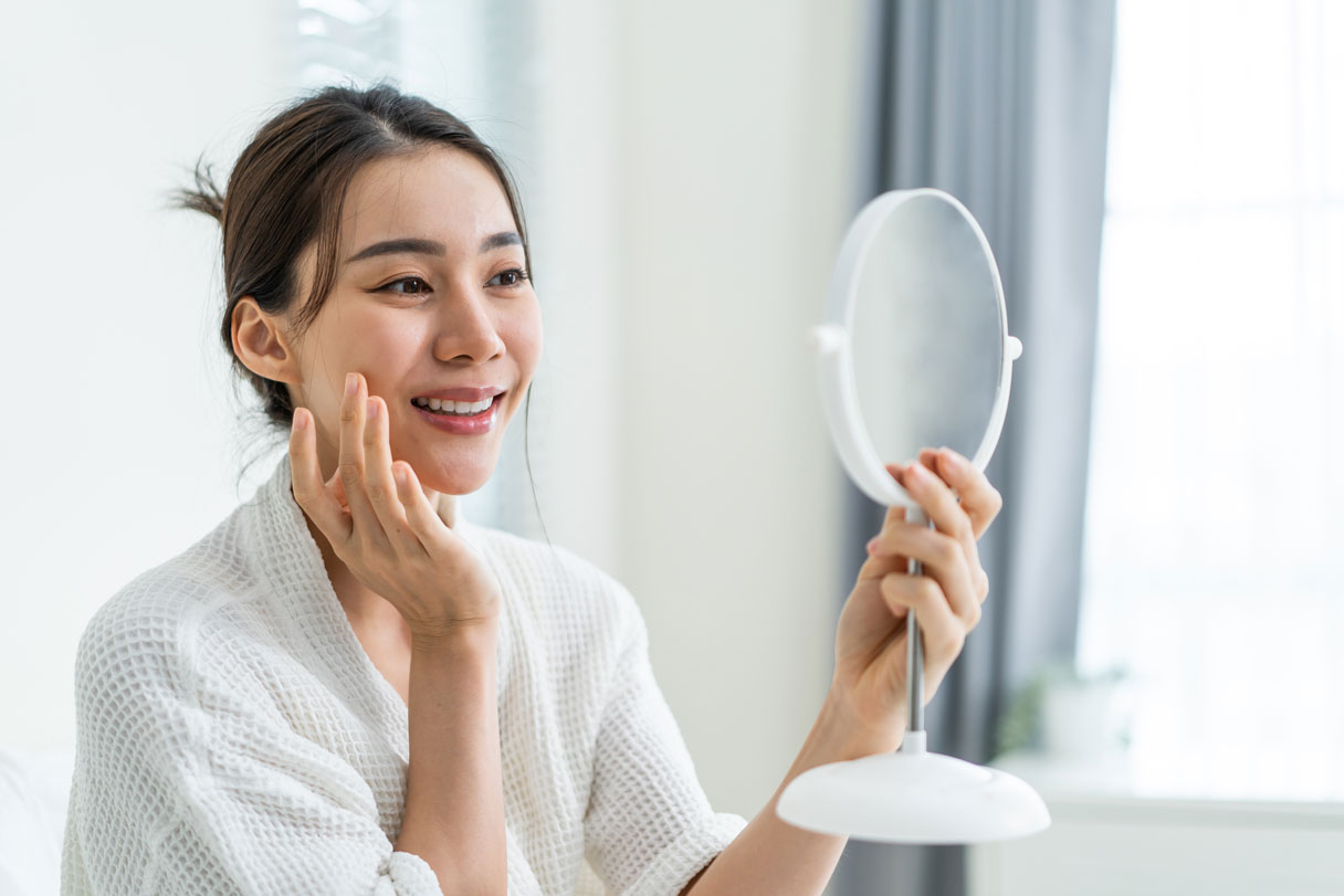 Smiling woman looking at herself in mirror