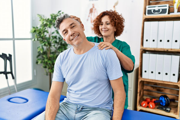 Chiropractor working on client's shoulders while he sits on adjustment table