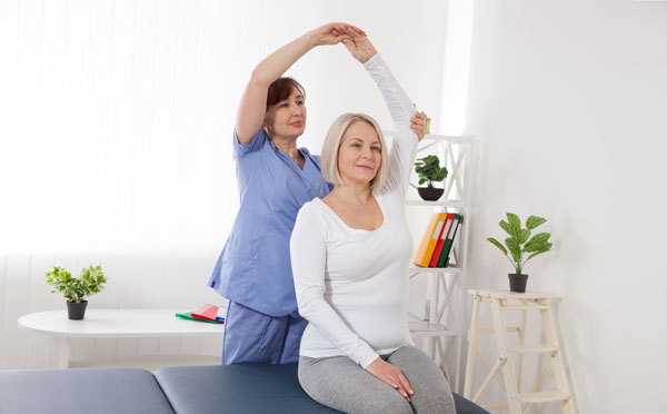 Chiropractor working with woman, stretching her arm