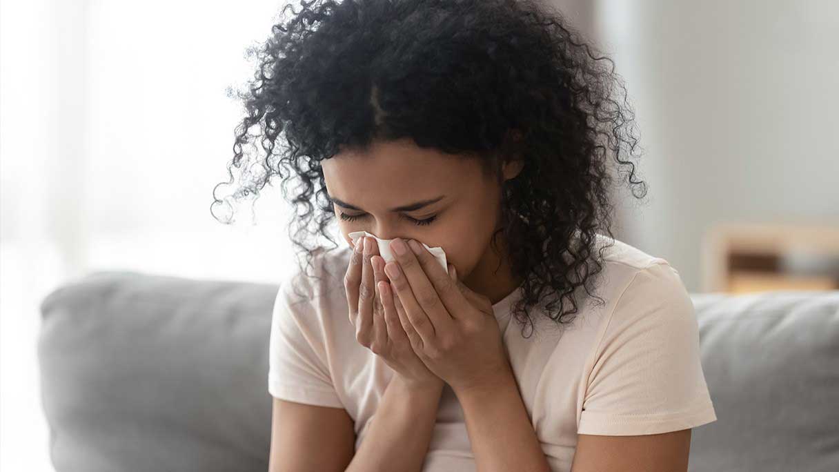 Woman blowing her nose into a tissue