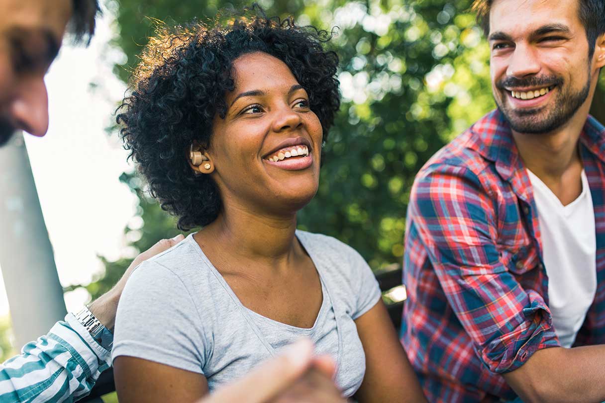 Two men and a woman sitting outside, smiling