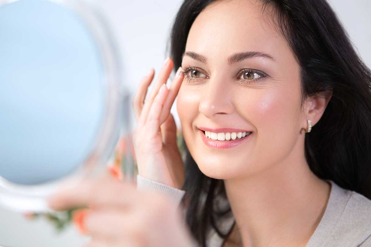 Smiling woman looking at herself in a mirror