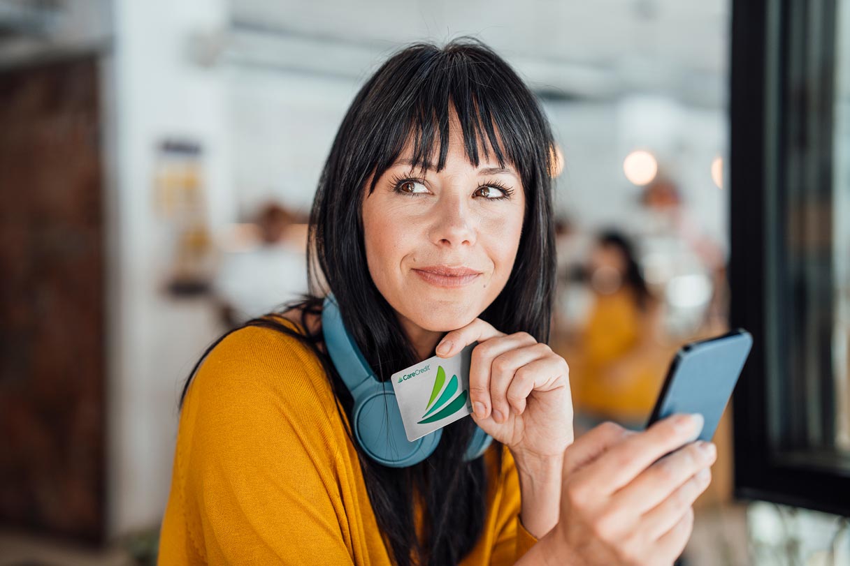 Woman holding CareCredit credit card and phone