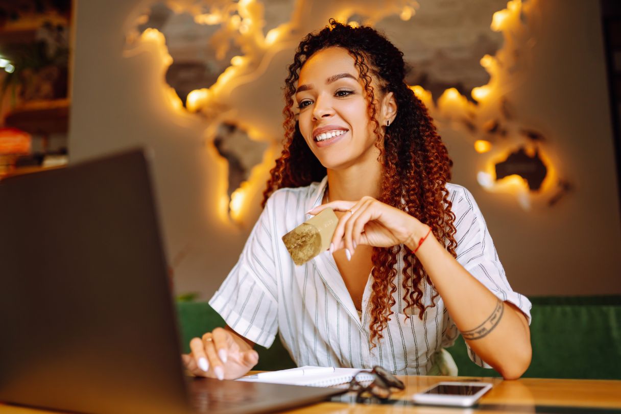 Woman holding credit card working on laptop