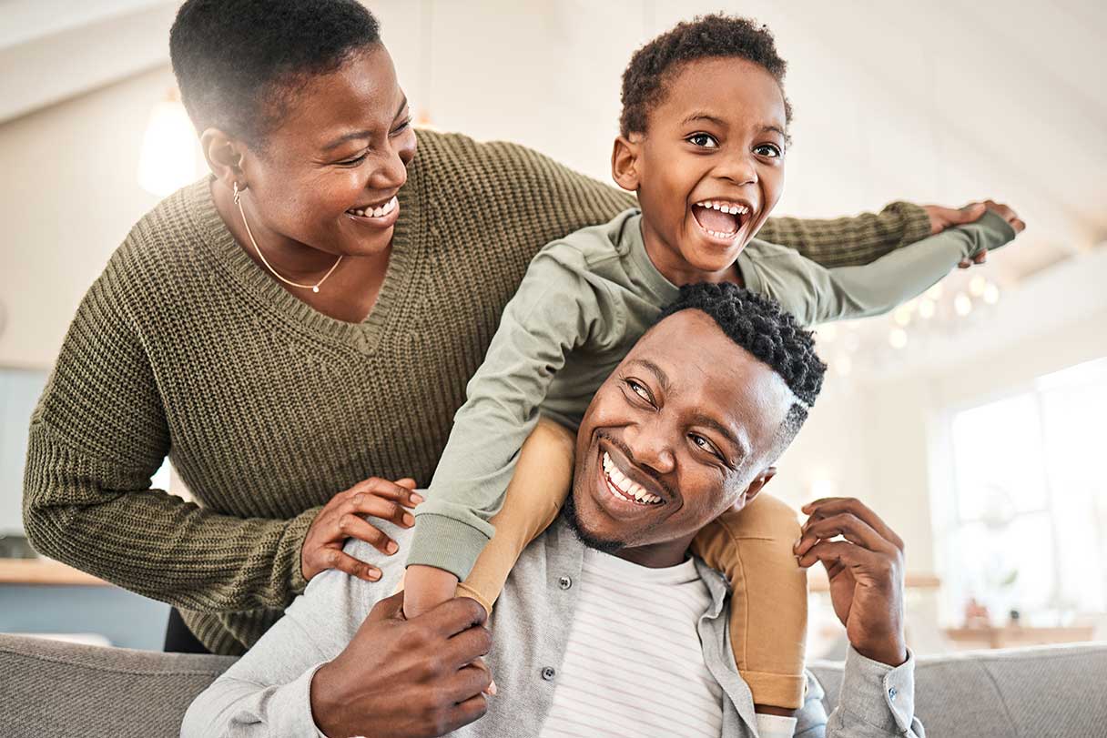 Man with child on his shoulders, smiling woman standing behind him