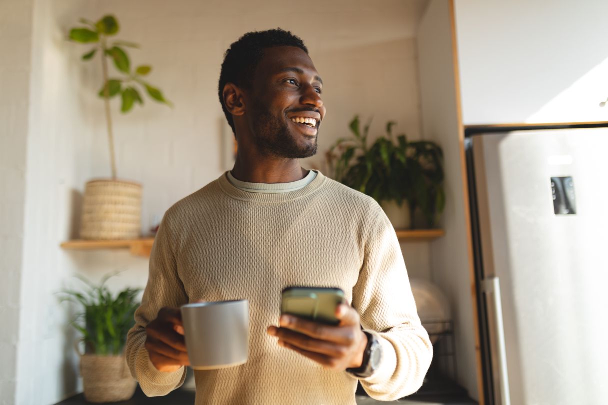 Smiling man holding phone and coffee