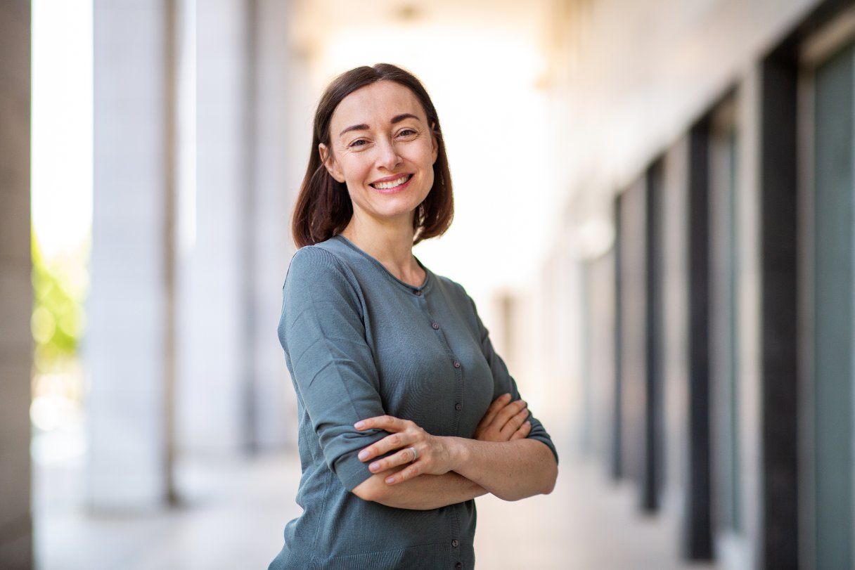 Smiling woman standing outside with arms crossed