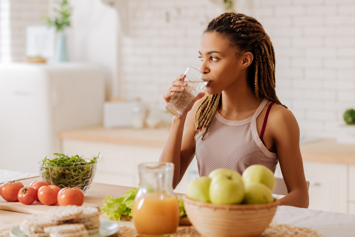 Woman next to fruit, drinking glass of water