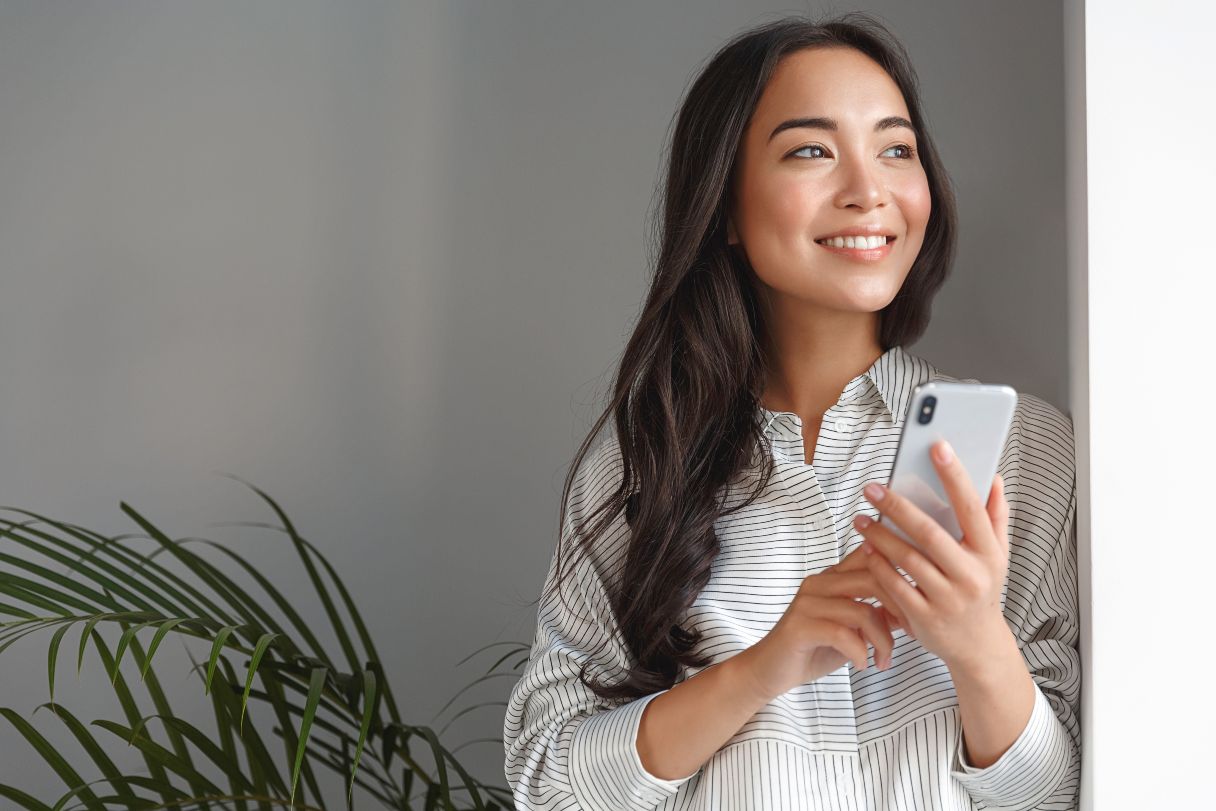 Woman on smart phone, smiling and looking out window