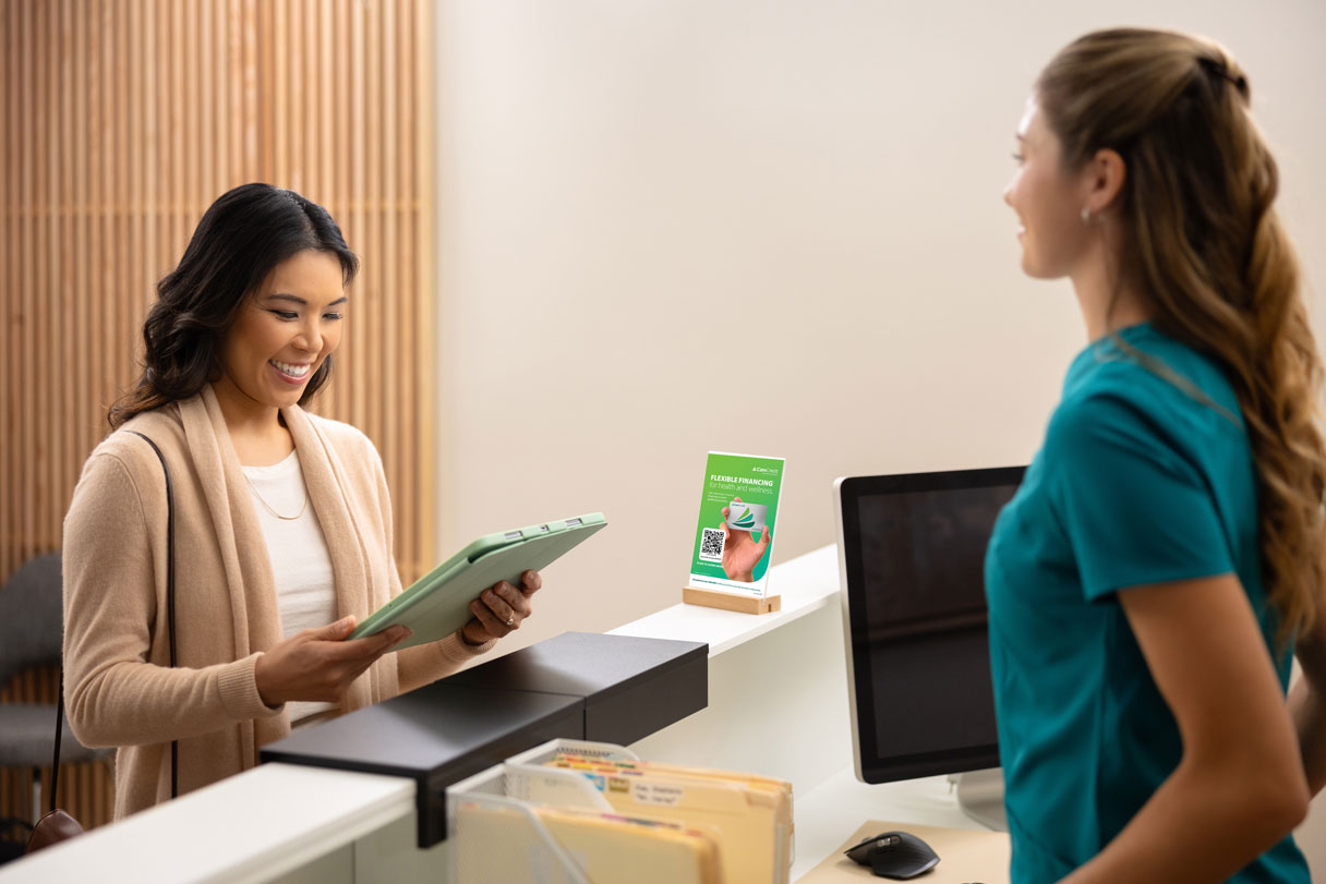 Woman looking at tablet in front of medical receptionist