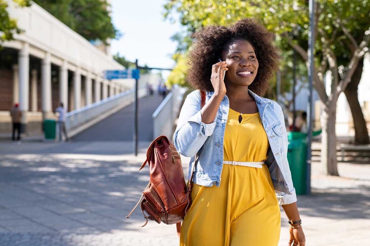 Woman smiling as she talks on a cellphone outside