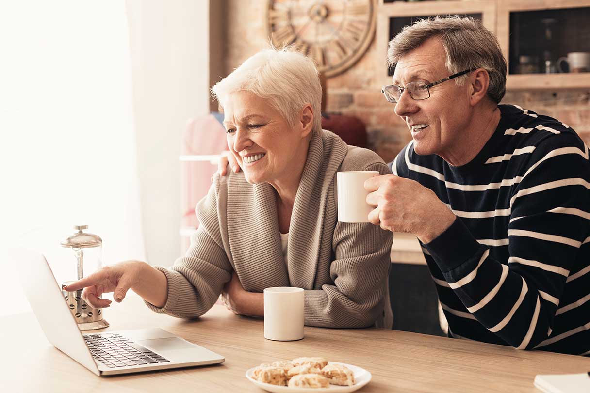 Senior couple looking at laptop while drinking coffee