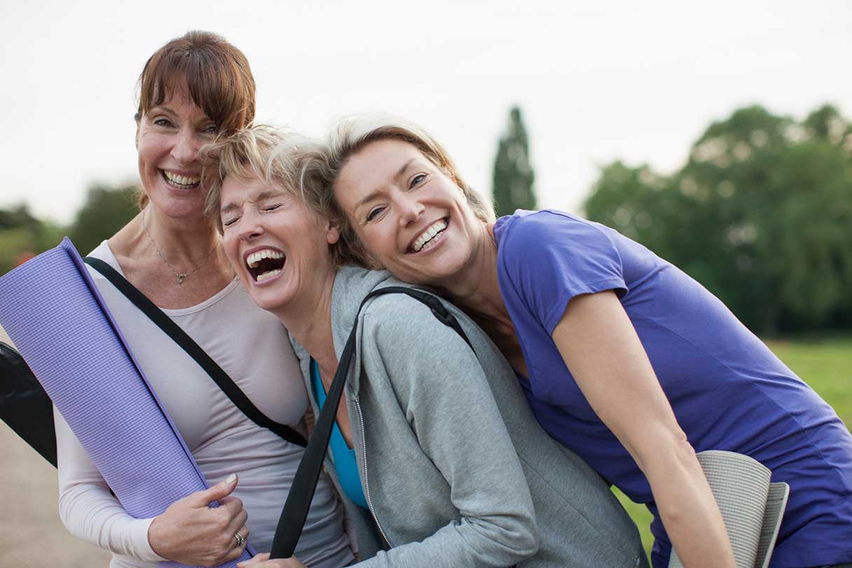 Laughing women with yoga mats