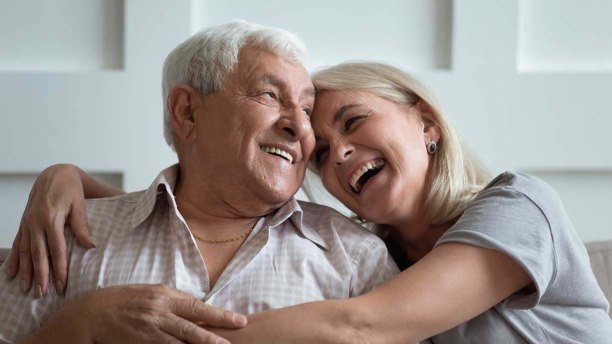 Senior couple laughing as they embrace