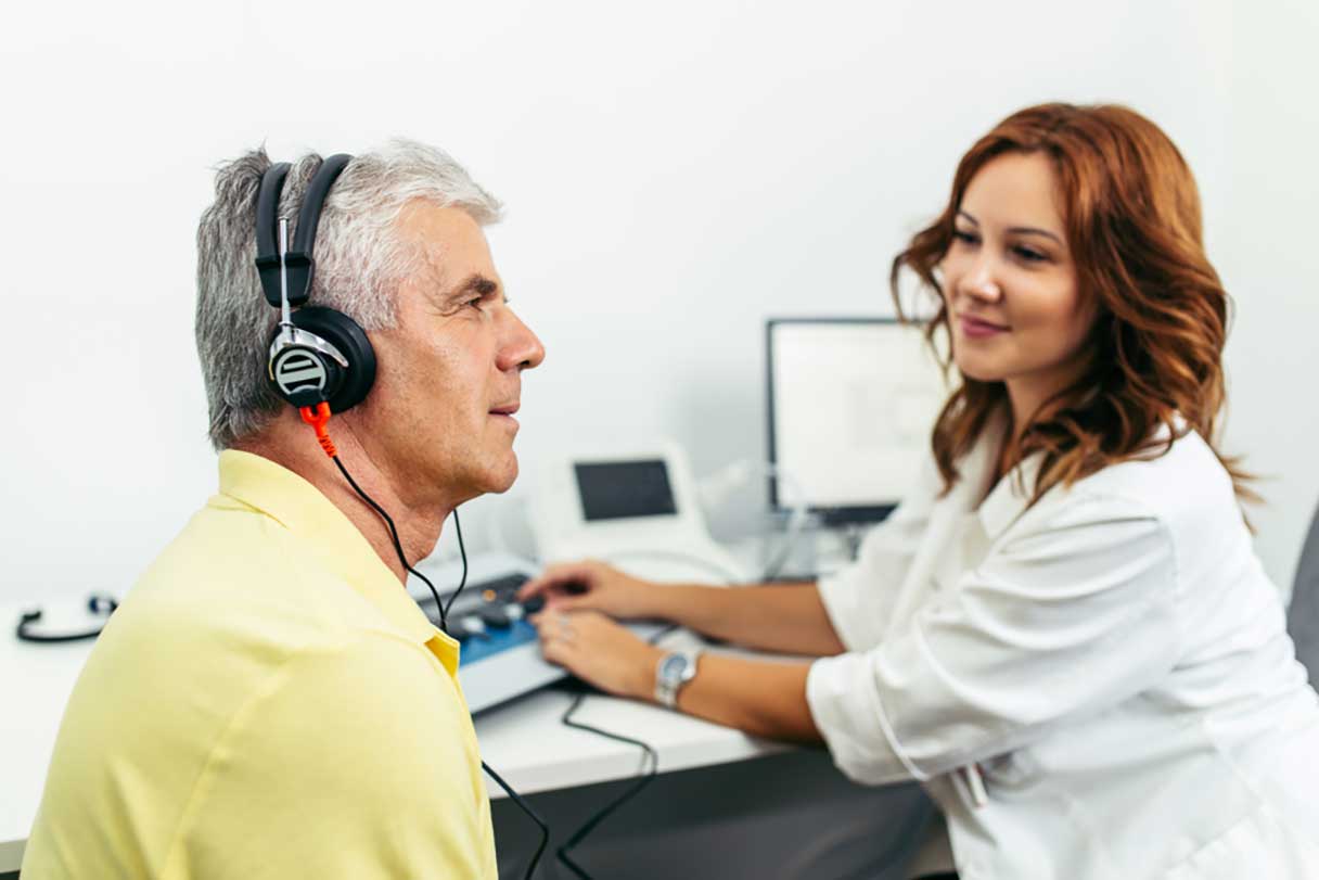 Woman conducting hearing test on man wearing headphones