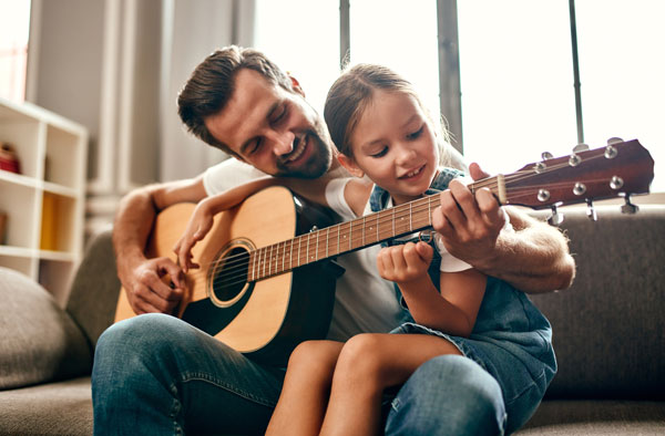 Man playing guitar with a young girl