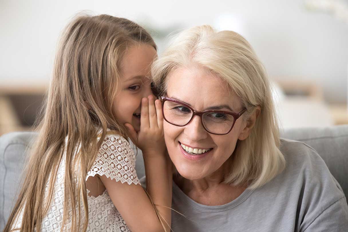 Young girl whispering in a woman's ear