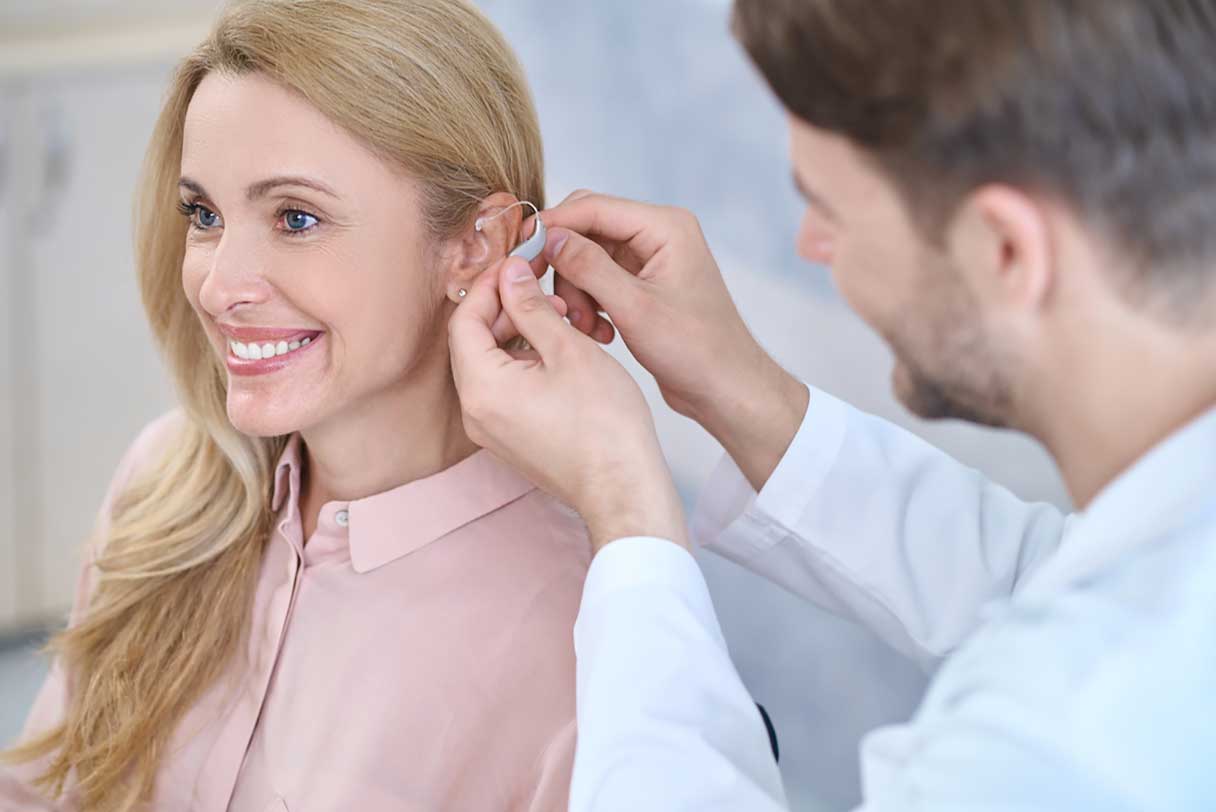 Smiling woman being fitted with a hearing aid