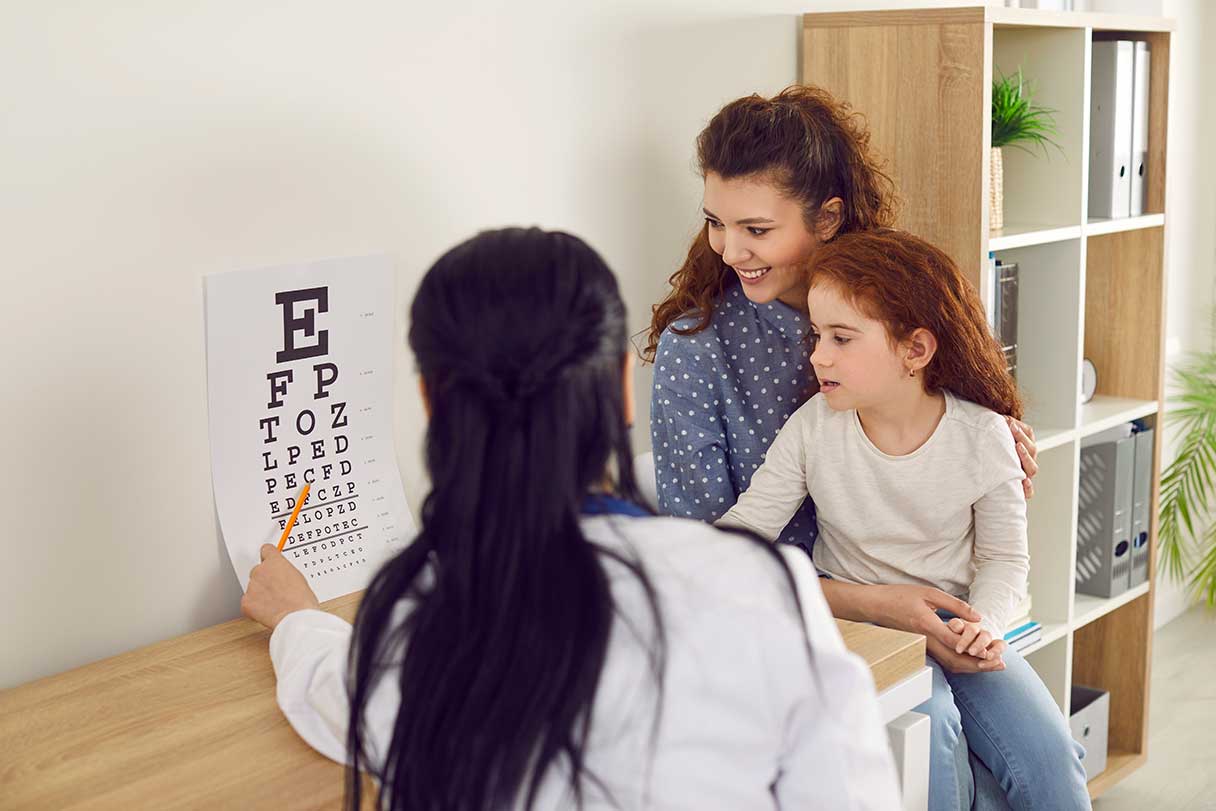 Optometrist performing eye exam on young girl