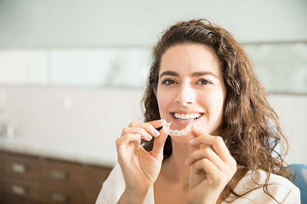 Woman holding mouth guard in front of her mouth