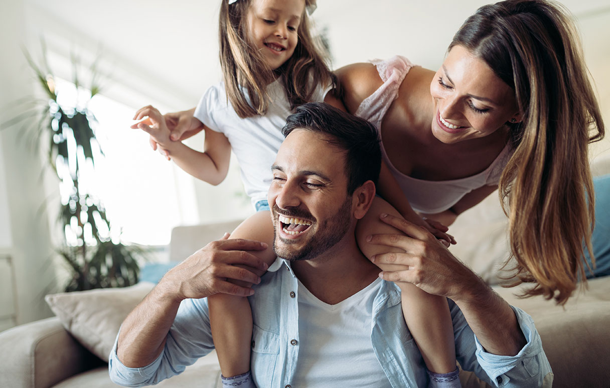 Man with young girl on his shoulders laughing with woman behind them
