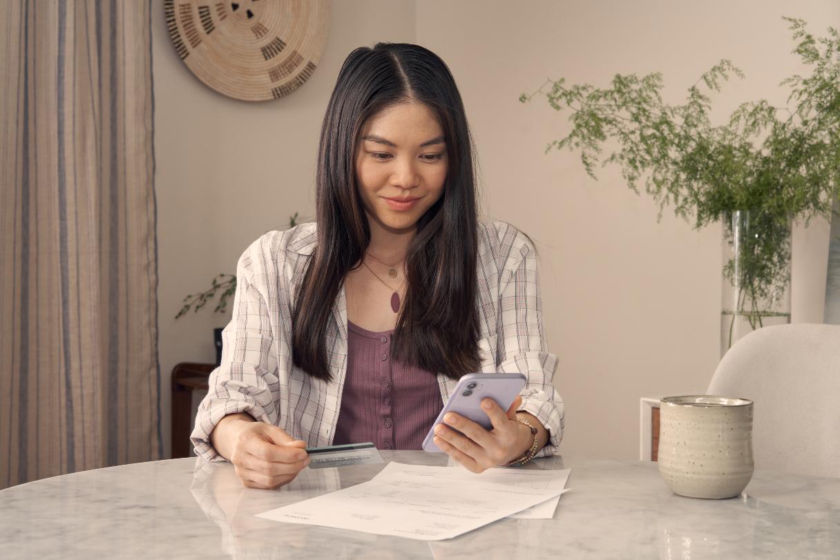 Woman holding a credit card as she looks at her phone